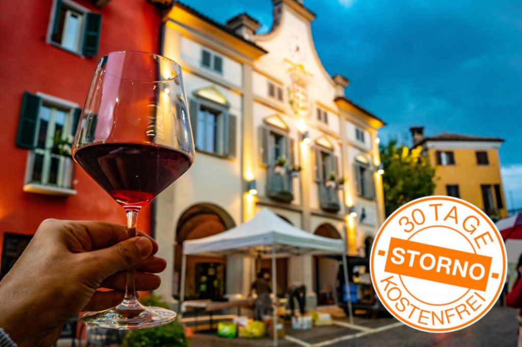 hand holding a glass of red wine in the town of Neive, Italy, on